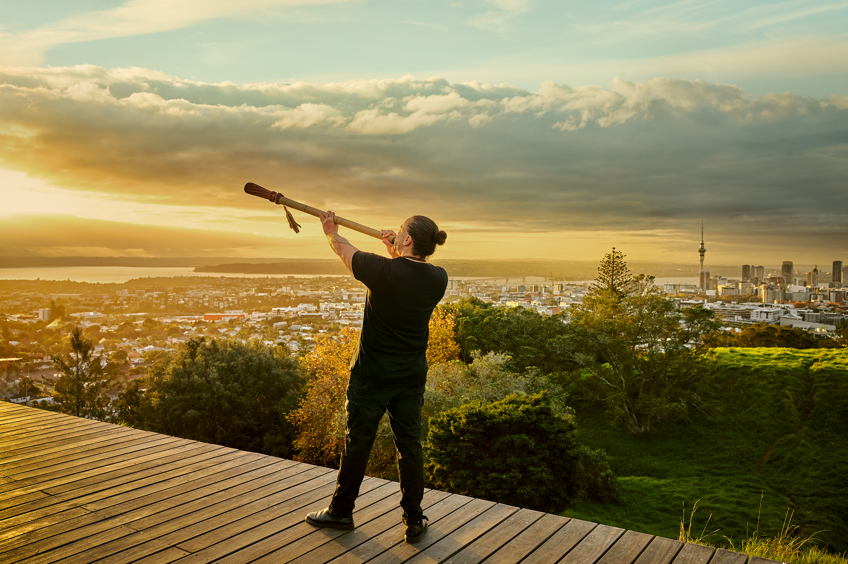 Man blows pūkaea (Māori instrument) on top of Maungawhau (Mt Eden)